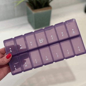 Purple pill organizer with labels for each day of the week.