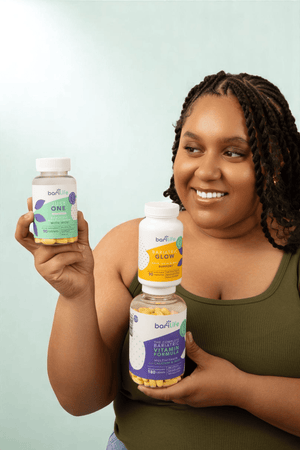Woman holding three bottles of barLife supplements, enhancing beauty and wellness, featuring vitamins and natural ingredients.