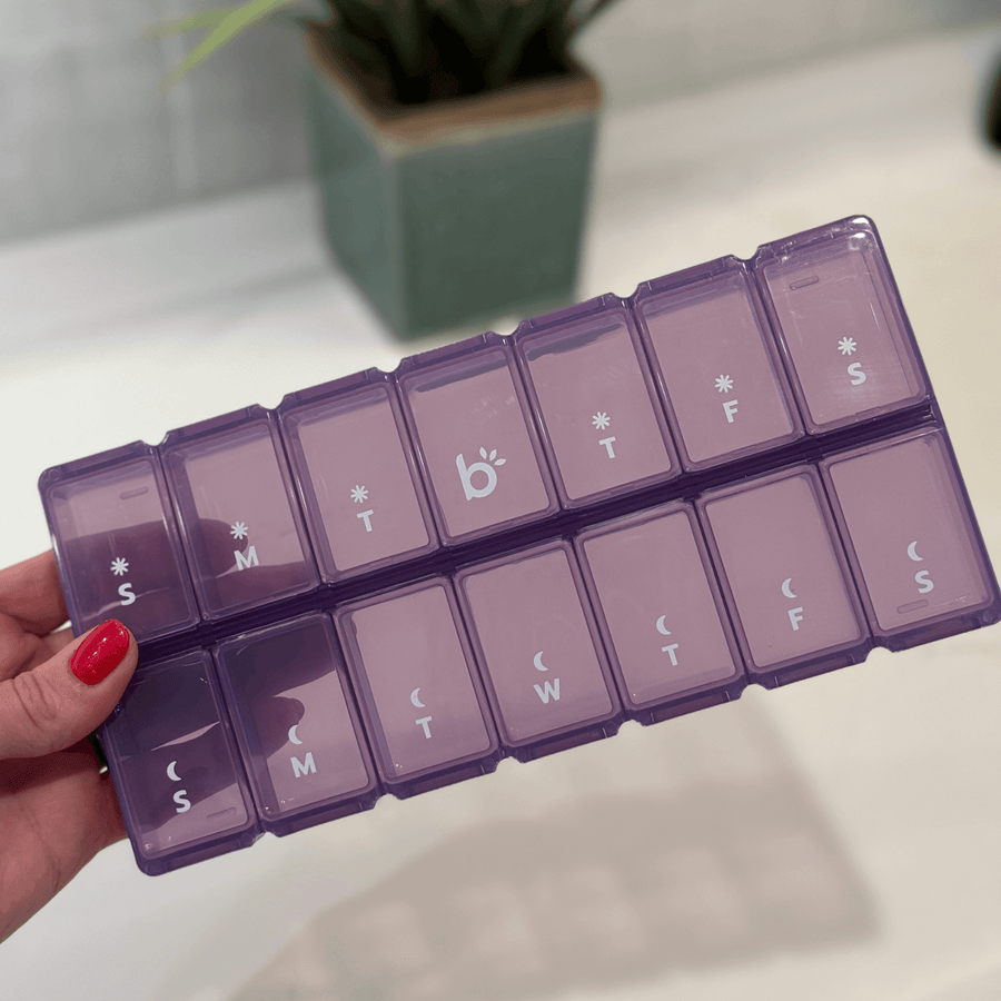 Purple pill organizer with labels for each day of the week.